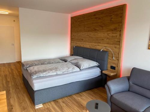 a bed in a room with a couch and a chair at Haus München in Bad Griesbach