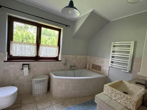 a bathroom with a tub and a toilet and a sink at Leśna 6 - House with a garden in Bolechowice