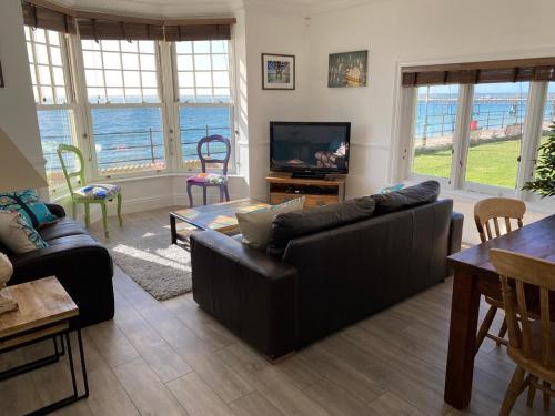 a living room with a couch and a television at Promenade Apartment with own Beach Hut in Totland