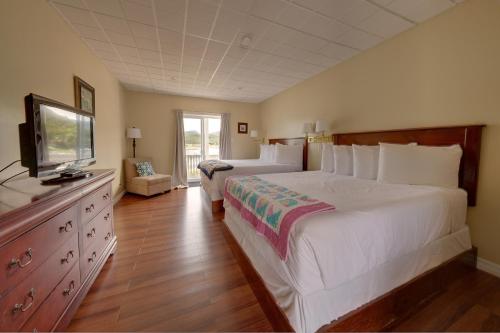 a bedroom with two beds and a flat screen tv at Gros Morne BaseCamp in Norris Point