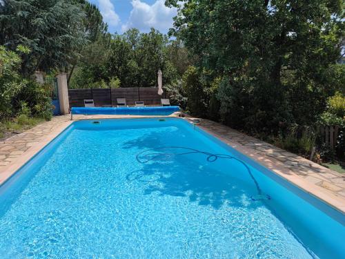 una piscina de agua azul en un patio en Appartement avec piscine chauffée, en Collobrières