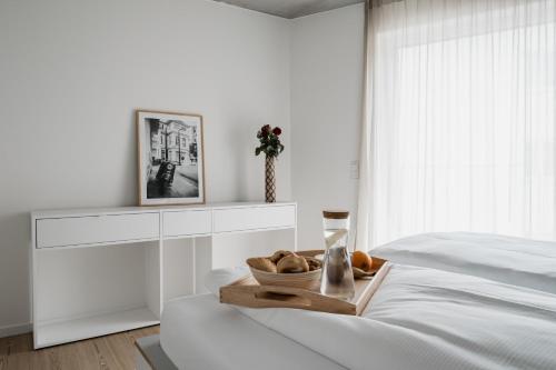 a white bedroom with a bowl of bread on a bed at CLOUD N°7 STUDIOS in Tübingen