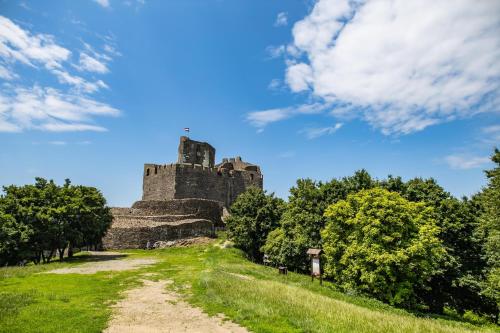a castle on a hill with a dirt road at Lankás Vendégház - Hollókő in Hollókő