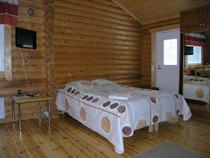 - une chambre avec un lit dans une cabane en rondins dans l'établissement Mertaranta, à Pääjärvi
