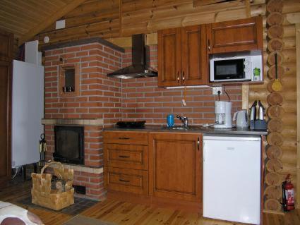 a kitchen with a brick fireplace and a white refrigerator at Mertaranta in Pääjärvi