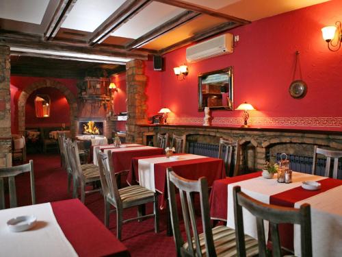 a restaurant with red walls and tables and chairs at Hotel Villa Viktorija in Banja Luka