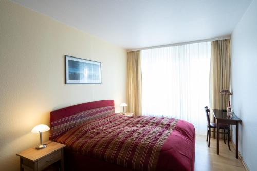Schlafzimmer mit einem Bett, einem Schreibtisch und einem Fenster in der Unterkunft Haus Meeresstrand Wohnung 207 in Scharbeutz