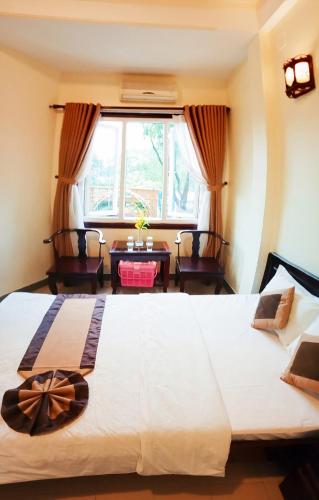 a bedroom with a large white bed and a window at Tran Ly Hotel in Hue
