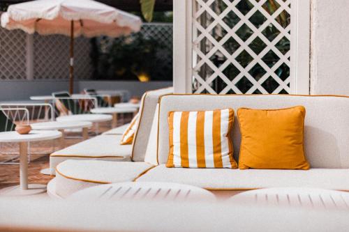 a white couch with a yellow pillow on a patio at Hotel des Lices in Saint-Tropez