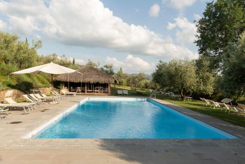 una piscina con una cabaña, sillas y una sombrilla en Il Palazzo - Agriturismo, Winery en Arezzo