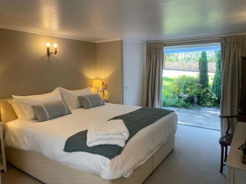 a bedroom with a large bed with a large window at Gorgeous Country Cottage on outskirts of Bath with Wood Fired Hot Tub in Midford
