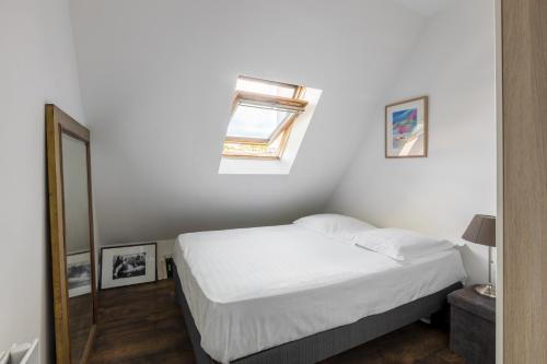 um quarto branco com uma cama e uma janela em Veeve - Footsteps from the Arc de Triomphe em Paris
