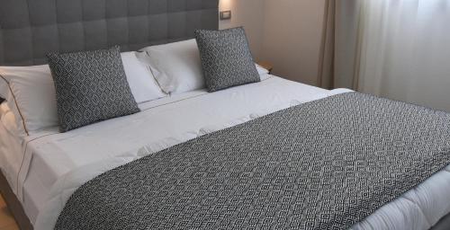 a large bed with gray and white pillows on it at Xenia Hotel in Villasimius