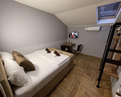 a room with a bed and a table and a ladder at Garni Ideal in Zrenjanin