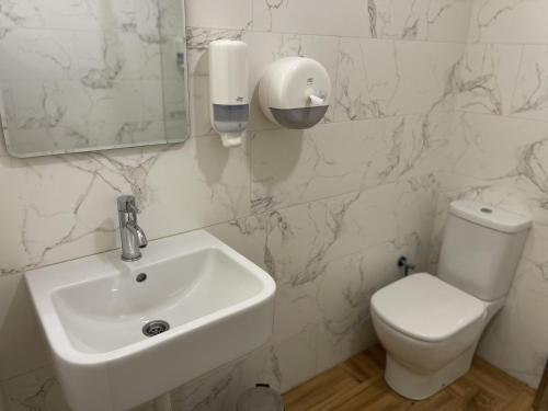 a white bathroom with a sink and a toilet at Garni Ideal in Zrenjanin