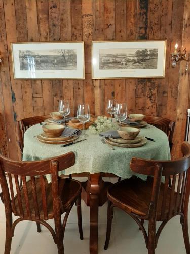 Gorssels Tuinhuis في Gorssel: طاولة طعام مع طاولة قماش خضراء وكؤوس للنبيذ