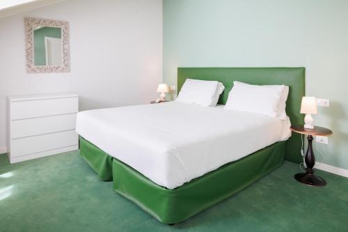 a bedroom with a large white bed with a green headboard at Antica Locanda Leonardo in Milan