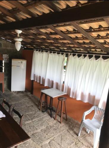 a room with a table and chairs and white curtains at Casa charmosa in Penedo