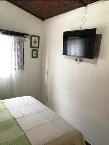 a bedroom with a bed and a flat screen tv at Casa charmosa in Penedo