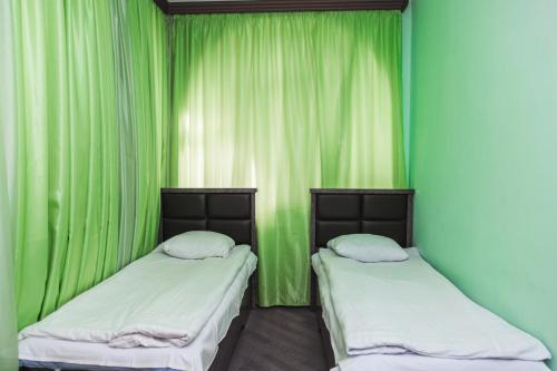 two beds in a room with green curtains at Syuniq Hotel in Goris