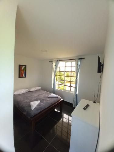 a small bedroom with a bed and a window at Alojamiento Sol de Maíz in Quimbaya