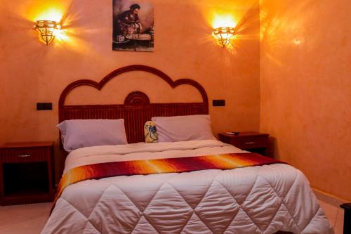 ein Bett in einem Schlafzimmer mit zwei Lichtern an der Wand in der Unterkunft Salma Palms Hôtel in Meski