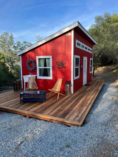 una casita roja pequeña con terraza de madera en McMillan Ranch Yosemite en Coarsegold