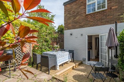 a patio with a table and chairs and a building at Adorable cottage with a log burner in heavenly village - Constable Lodge in Nayland