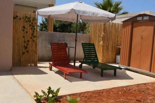 two lawn chairs and an umbrella on a patio at Joy's house in Kato Gouves