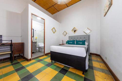 ein Schlafzimmer mit einem Bett und ein Badezimmer mit einem Klavier in der Unterkunft Ayenda Sarayu House in Medellín