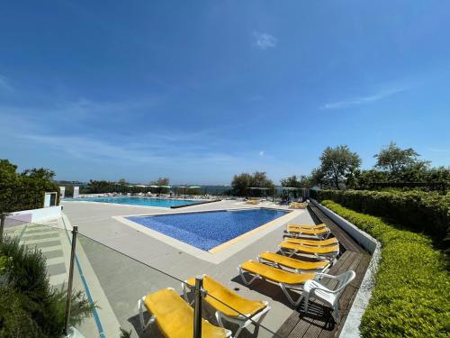 a group of yellow lounge chairs next to a swimming pool at Village Vacances Lo Solehau in Balaruc-les-Bains