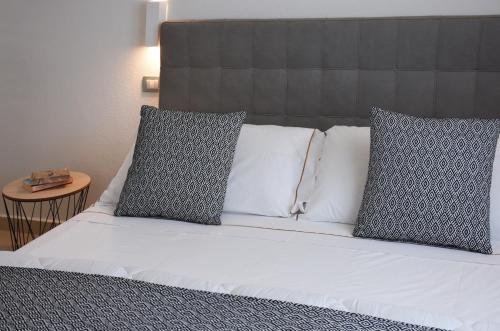 a bed with three pillows on top of it at Xenia Hotel in Villasimius