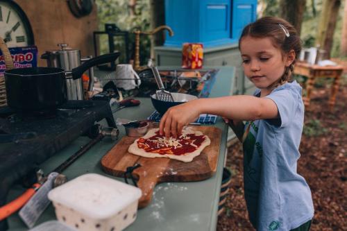 una joven haciendo una pizza en una tabla de cortar en The Sleepy Explorer en Hallaton
