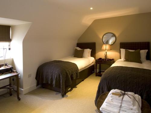 ギルフォードにあるThe Percy Armsのベッド2台と鏡が備わるホテルルームです。