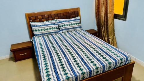 een bed met een blauwe en witte quilt bij JIKKE Appartement in Dakar