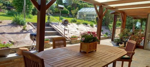 un patio con mesa de madera y sillas y un jardín en Gîte Les Sittelles, en Tenneville