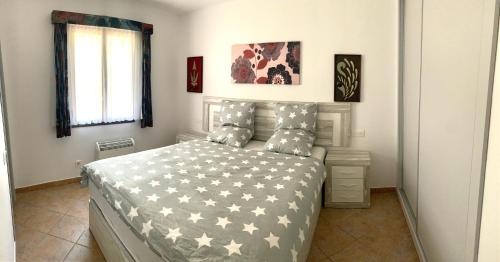 a bedroom with a bed with a gray and white comforter at Gerry&Lotti Apartment in Son Bou