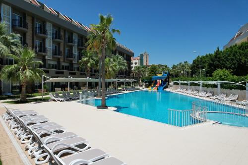 a large swimming pool with lounge chairs and a hotel at Camyuva Beach Hotel in Kemer