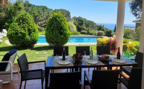 a dining table and chairs on a patio with a pool at Villa Max in Lloret de Mar