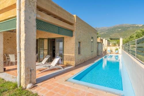 a villa with a swimming pool next to a house at Villa Mediterranea, with heated pool in Livadia