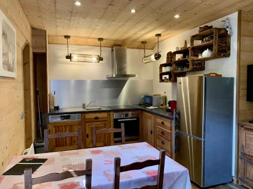 a kitchen with a table and a stainless steel refrigerator at Appartement avec jacuzzi dans chalet privé, grande terrasse, parking gratuit in Les Houches