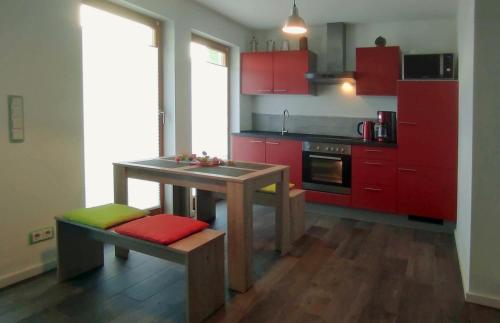 a kitchen with red cabinets and a table with a bench at Stylische Ferienwohnung Home Office in Wiesbaden