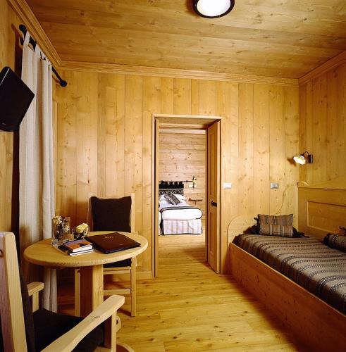 a bedroom with a bed and a table with a laptop at Hotel Baita Dei Pini in Bormio