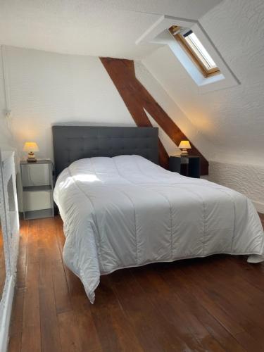 une chambre avec un grand lit blanc dans un grenier dans l'établissement la Perle Bleue, à Outreau