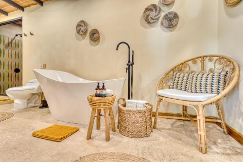 a bathroom with a tub and a chair and a toilet at awā Beachfront Hotel in Puerto Viejo