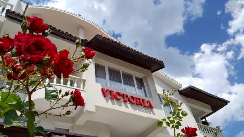 een bord aan de zijkant van een gebouw met rode rozen bij Victoria Family Hotel in Balchik