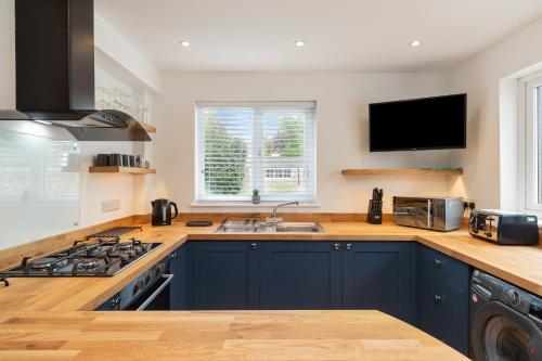 a kitchen with blue cabinets and a sink and a tv at Falcon House in Pembroke Dock