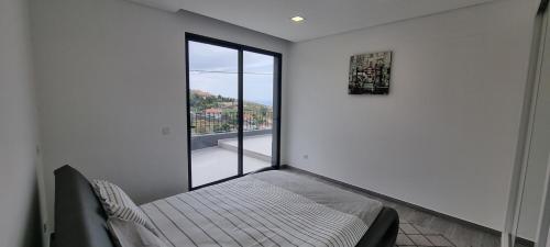 Cette chambre comprend un lit et une grande fenêtre. dans l'établissement Villa Castanho I, à Calheta