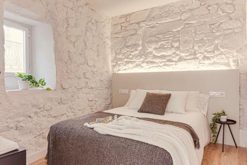 a bedroom with a bed with a stone wall at Old Quarter Boutique in A Coruña