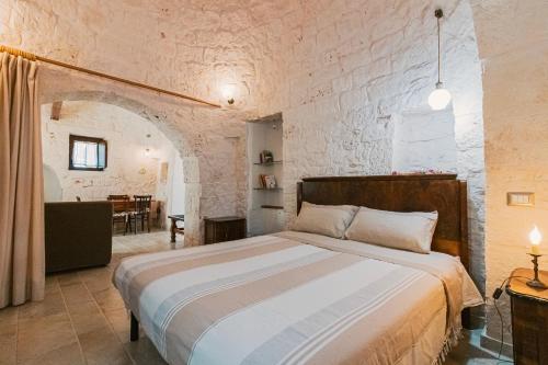 a bedroom with a large bed in a stone wall at Trulli Tiche in Cisternino
